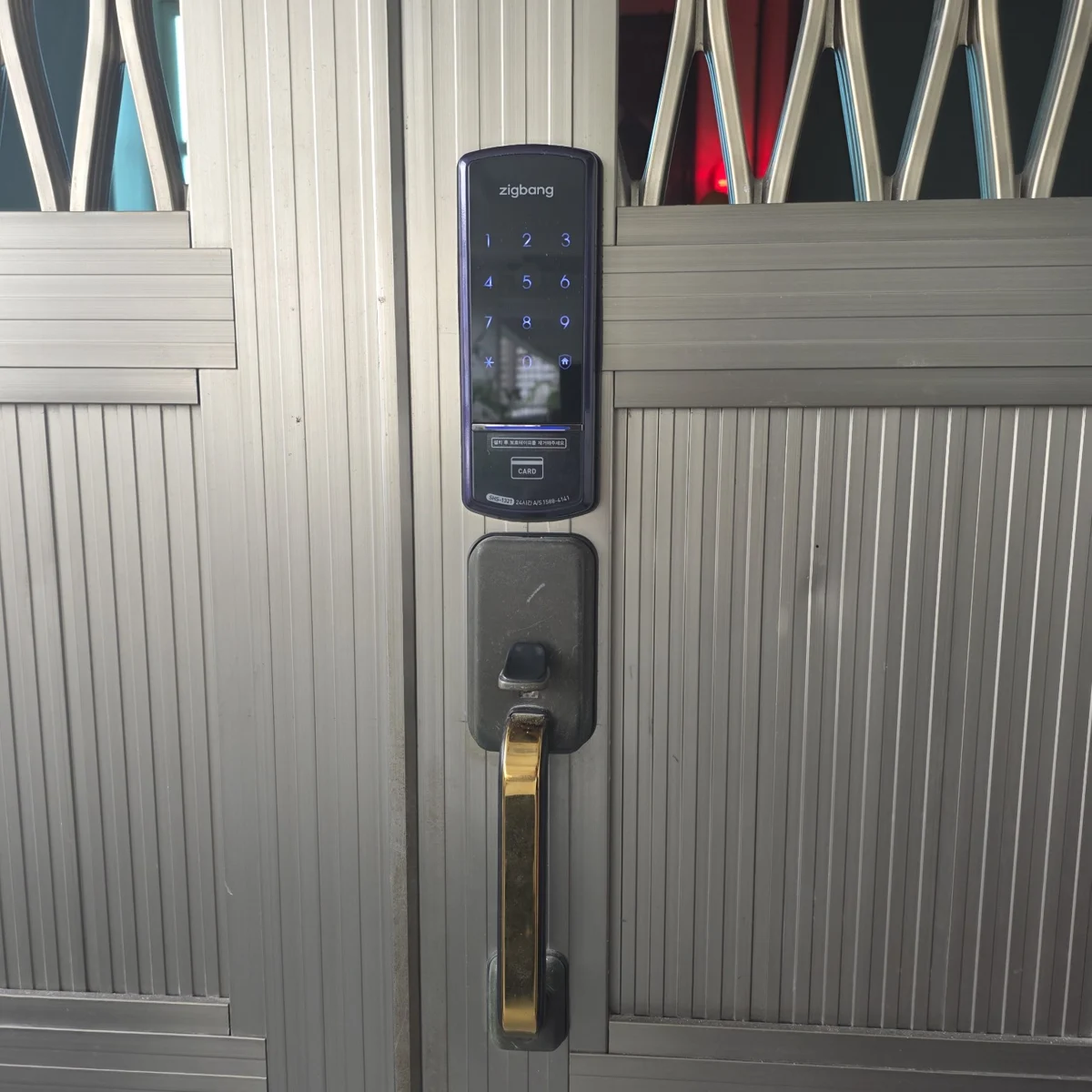 Zigbang 1321 Digital Lock fitted to a metal entrance door above the existing handle
